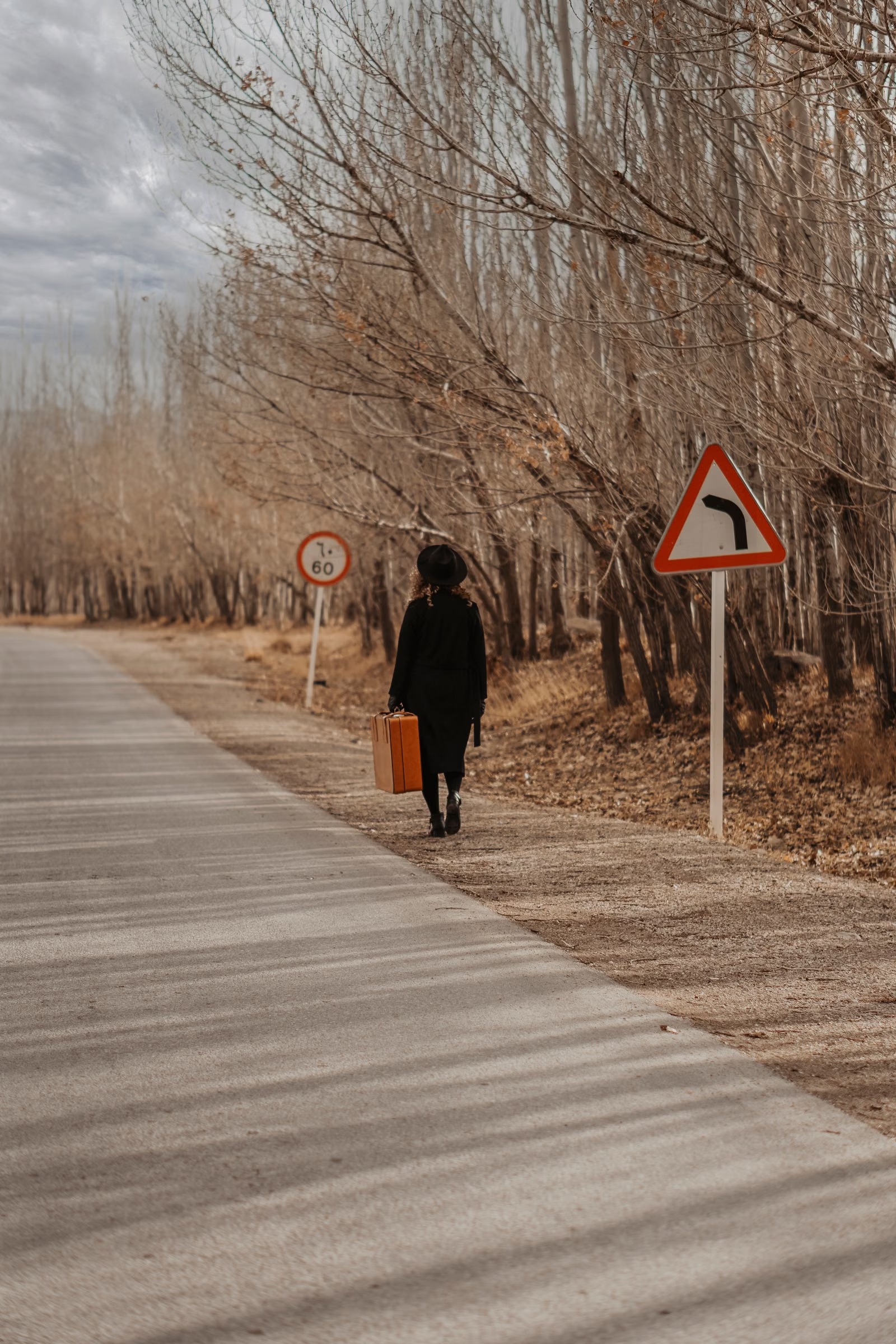 秋季公路旁提着行李箱的旅行者